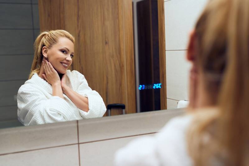 Young woman smiling at her reflection in a mirror